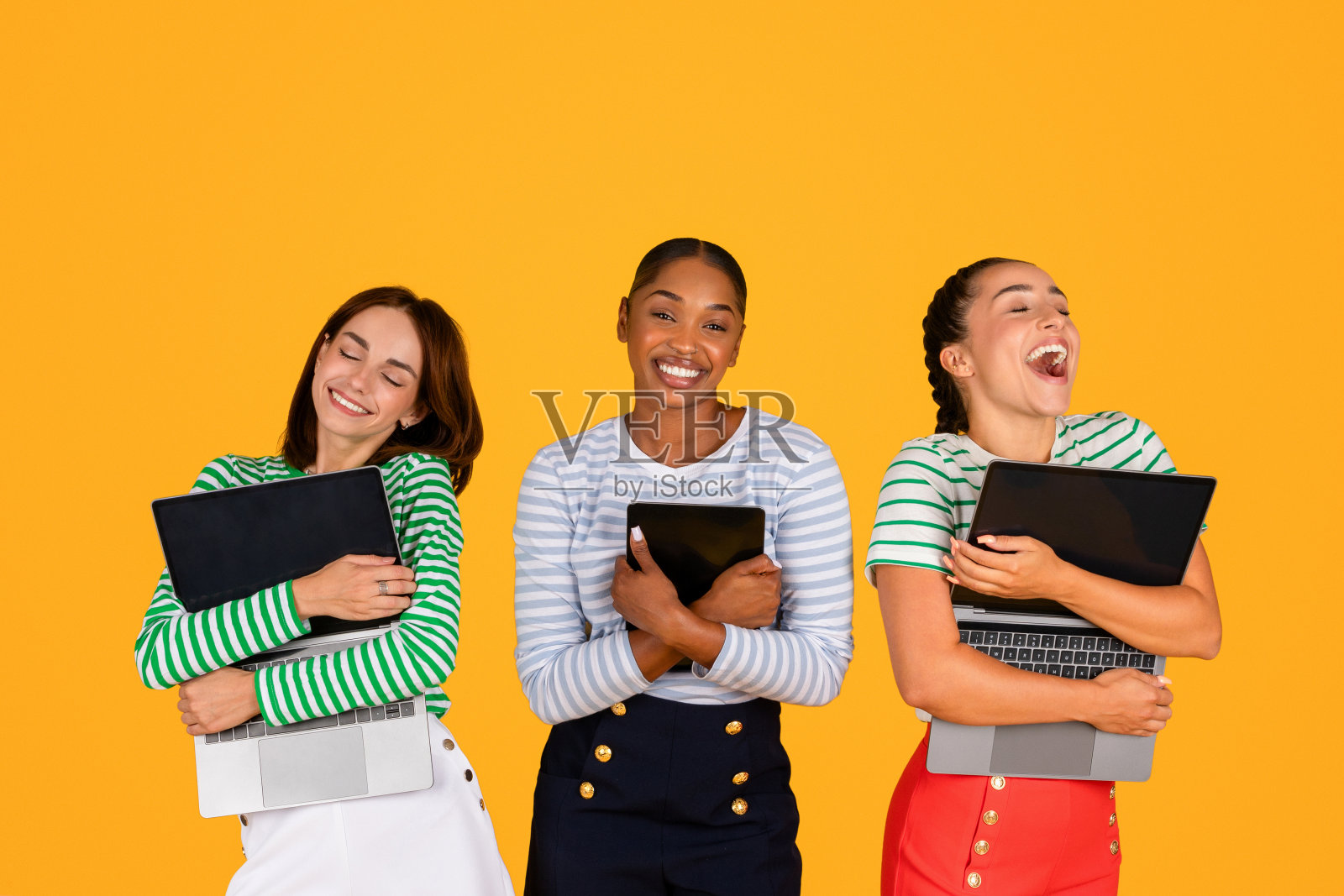 激动的年轻多种族女性抱着小玩意，黄色背景照片摄影图片