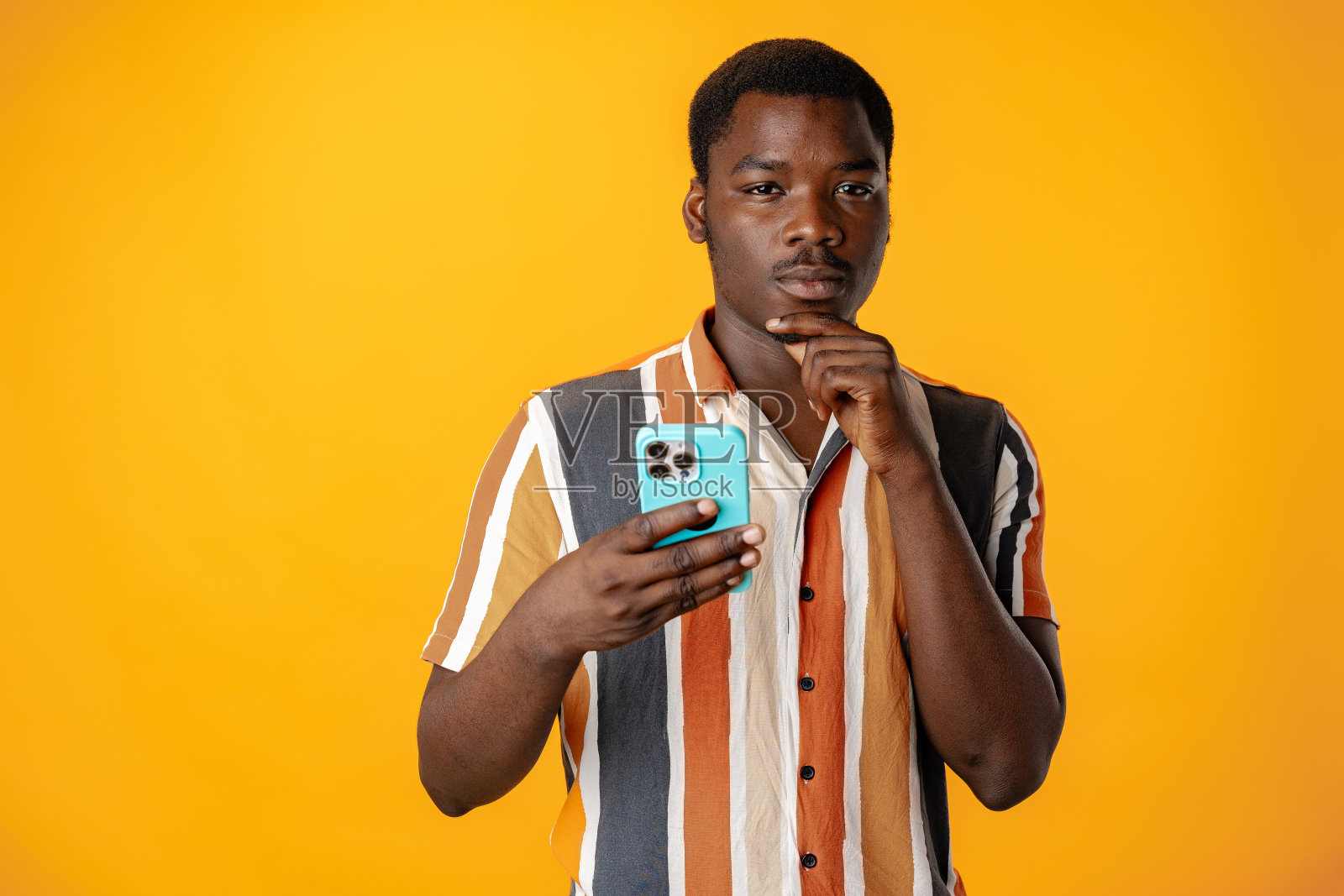 年轻的非洲男子在黄色背景下使用智能手机照片摄影图片