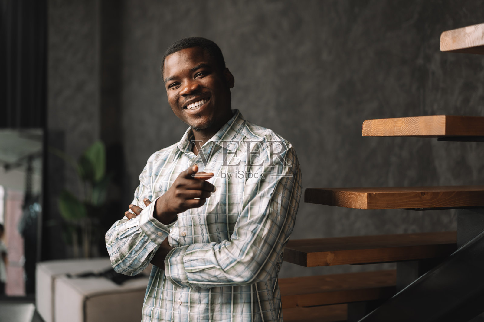 自信的年轻非洲商人站在木梯肖像旁照片摄影图片