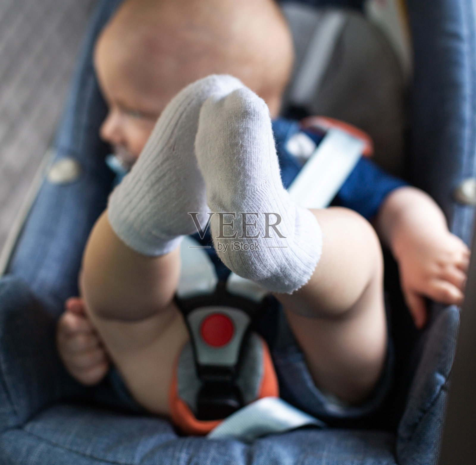 一个英俊的小男孩系着安全带坐在儿童汽车座椅上。用汽车运送儿童时的安全概念。照片摄影图片