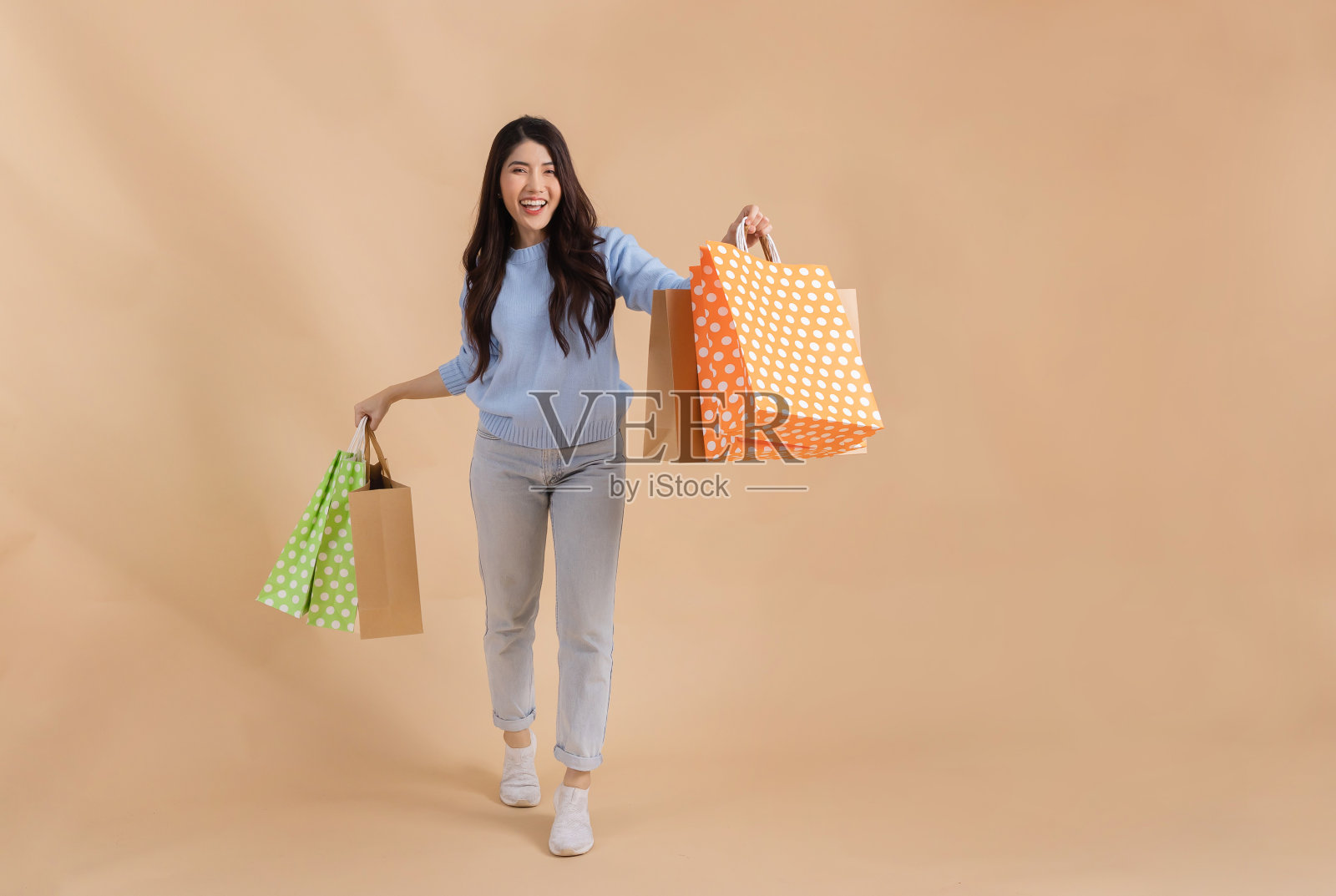 开心微笑的亚洲女购物者拿着一堆购物袋看着镜头，笑得很开心。-全身长度照片摄影图片