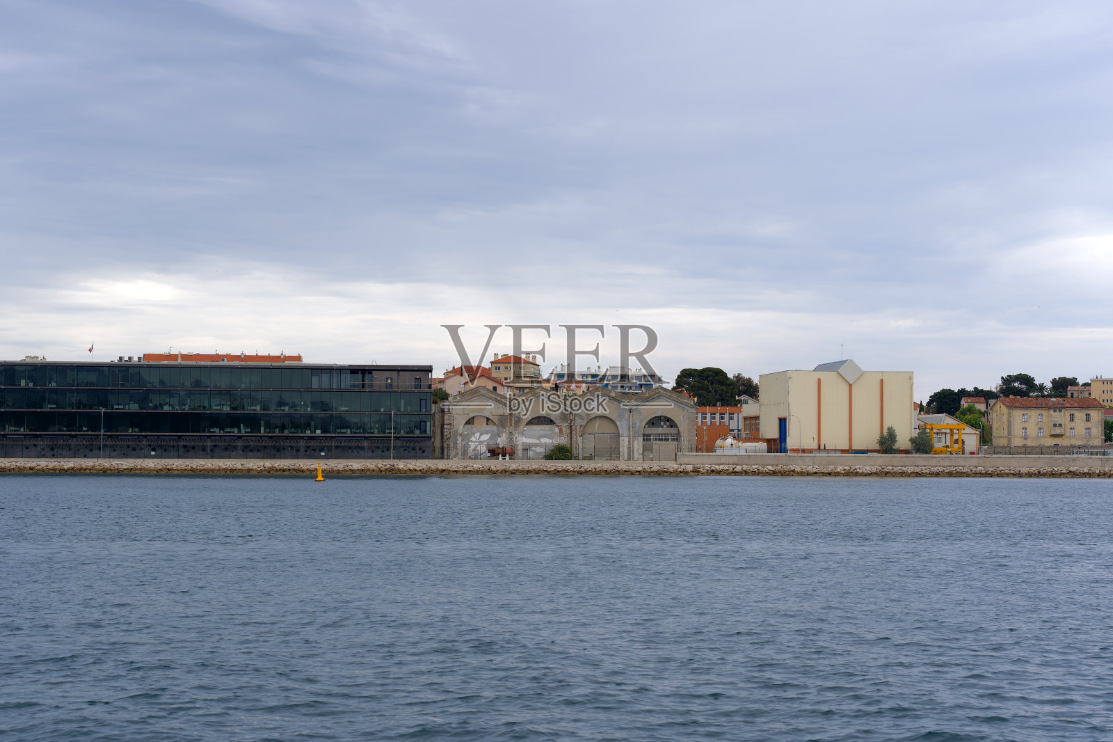 法国南部城镇码头工业建筑的风景，前景是海洋。照片摄影图片