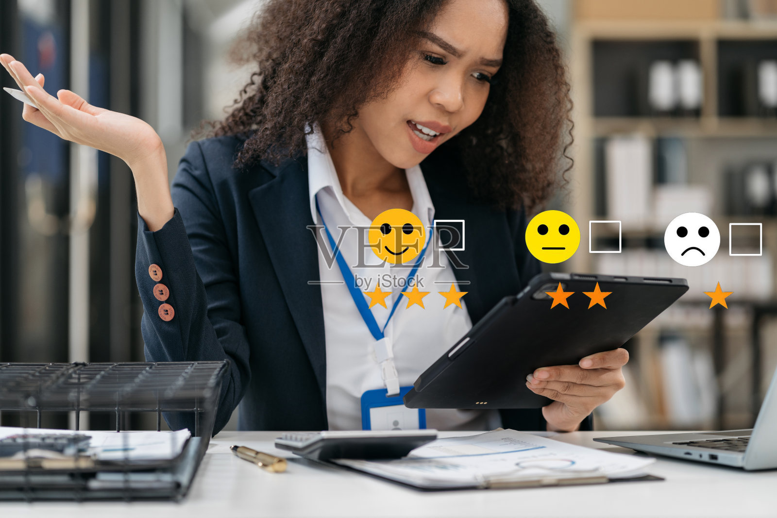 快乐的非洲妇女拿着一个数字平板电脑，上面的复选框对笑脸进行了评分，这对于满意度调查、快乐的客户体验概念来说是非常好的。照片摄影图片