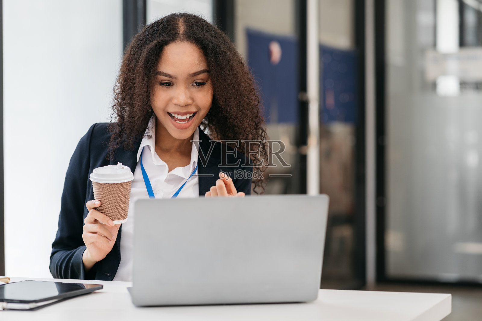 快乐的非洲妇女拿着手机看着屏幕挥手视频呼叫朋友在线在移动聊天应用程序使用笔记本电脑视频聊天应用程序。照片摄影图片