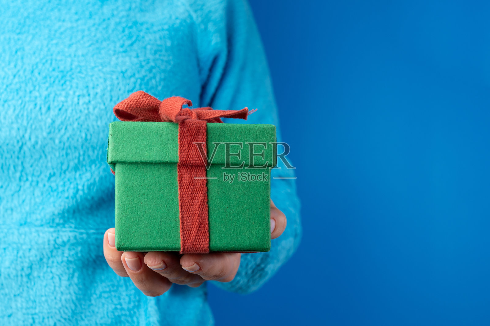 手拿蓝底礼盒，圣诞礼物，彩带包裹，新年惊喜，欢欢喜喜庆祝照片摄影图片