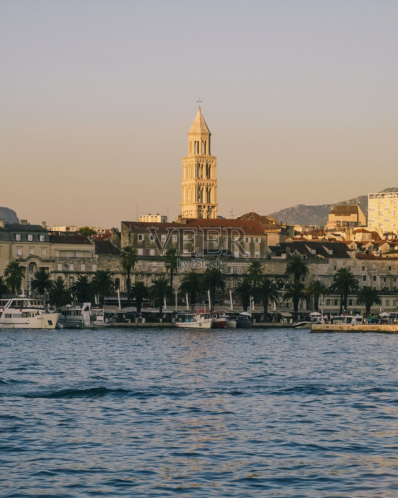 一座高耸在城市上空的钟楼，倒影在水中，斯普利特城照片摄影图片