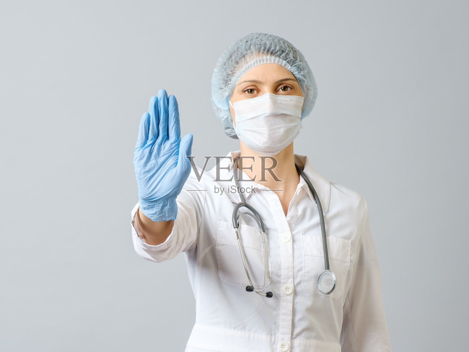 医生戴着医用口罩和一次性手套，做出停止手势照片摄影图片