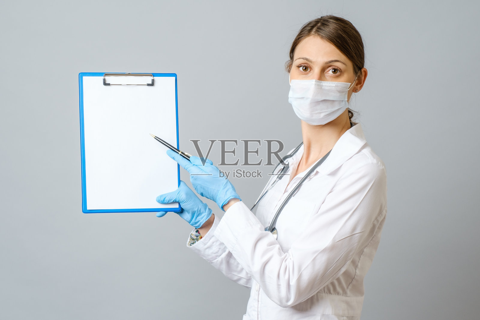 女医生戴着防护口罩，展示着剪贴板照片摄影图片