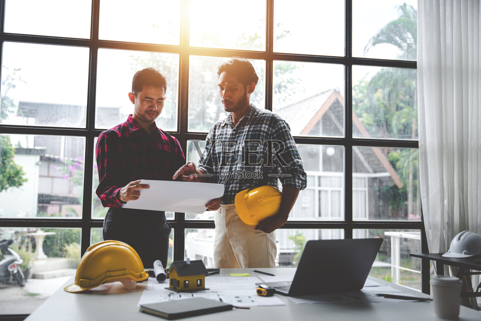 工程师们作为一个团队工作，为建筑计划绘制蓝图。工程师用建筑设备勾勒建筑项目概念建筑师在餐桌上谈论团队合作和建筑概念照片摄影图片