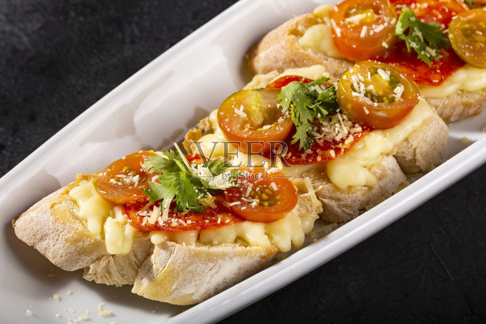 开胃菜或开胃菜——意式烤面包配上西班牙香肠片，配上法式面包，配上圣女果和马苏里拉奶酪照片摄影图片