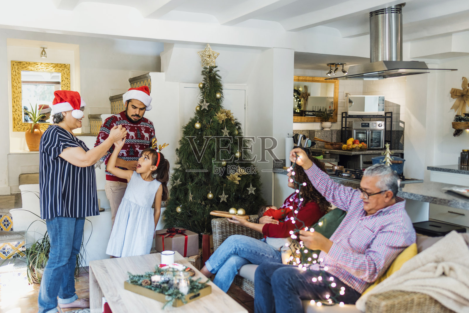 拉丁美洲墨西哥的西班牙家庭，父母和女儿与祖父母在家里装饰圣诞树照片摄影图片