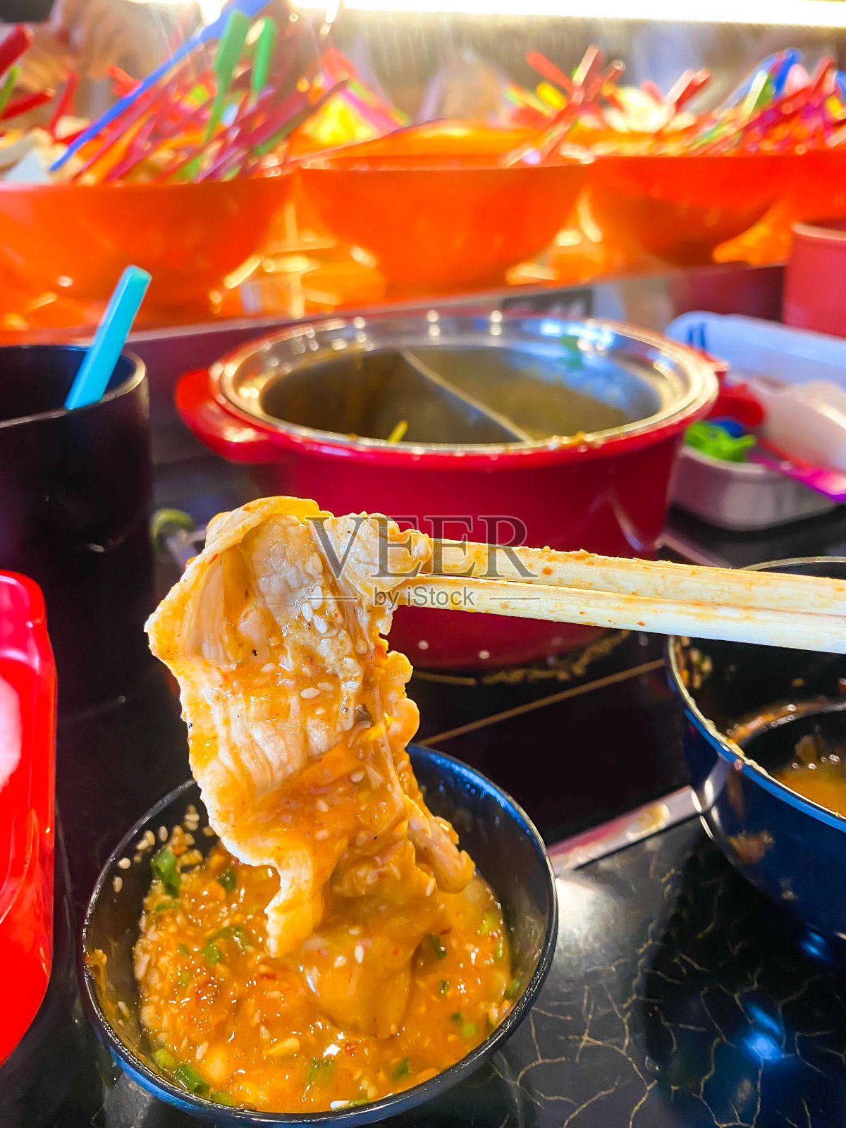 手握筷子与熟猪肉在涮涮锅和寿喜烧火锅。食物概念与美食日本火锅料理。照片摄影图片