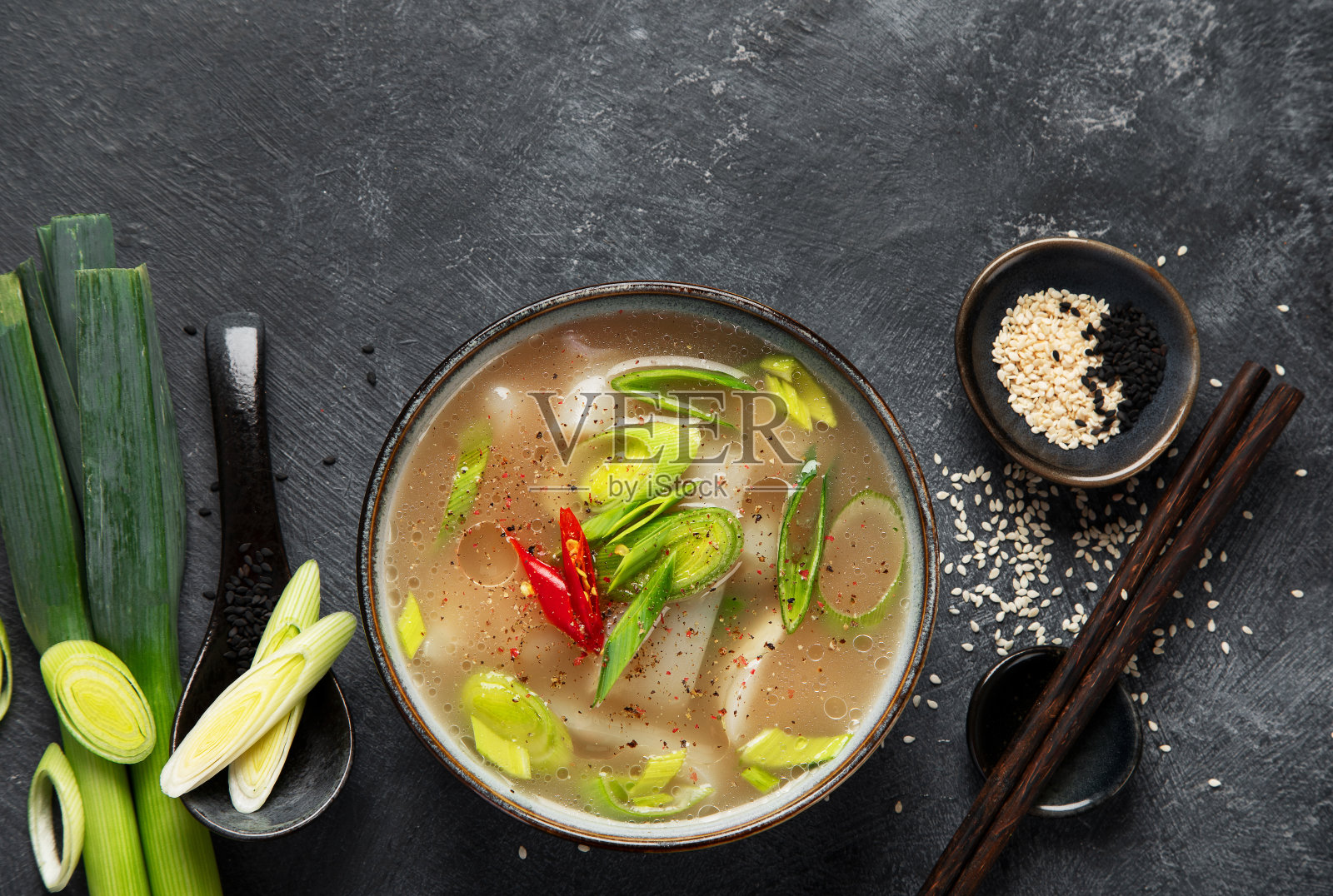 一碗韭菜汤，暗底辣椒。食品的概念照片摄影图片