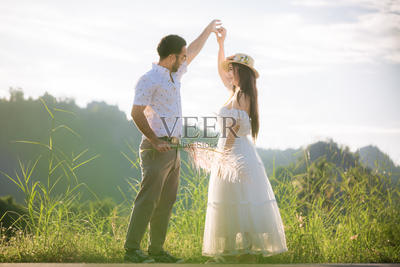 在大自然中跳舞的年轻情侣，身着传统巴伐利亚服饰的年轻情侣和身穿紧身连衣裙的年轻女子在大自然中跳舞照片摄影图片
