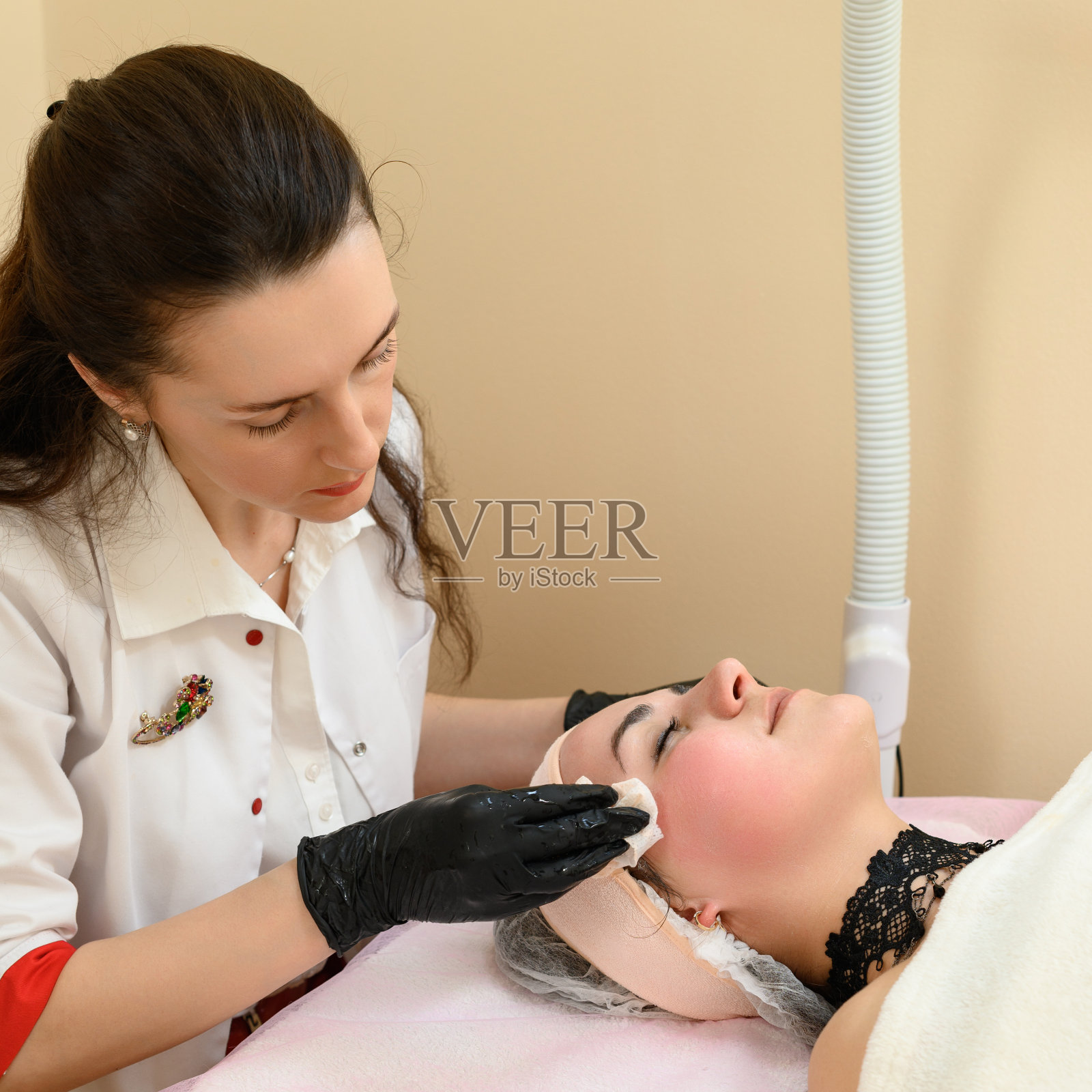 美容师用餐巾擦掉脸上残留的面霜。照片摄影图片