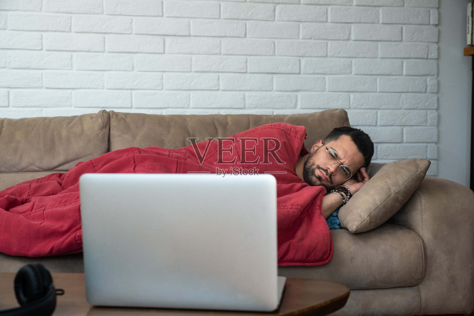 感到沮丧和焦虑的自由职业商务男，等待新项目的结果。裹在毯子里的男学生有心理健康问题照片摄影图片