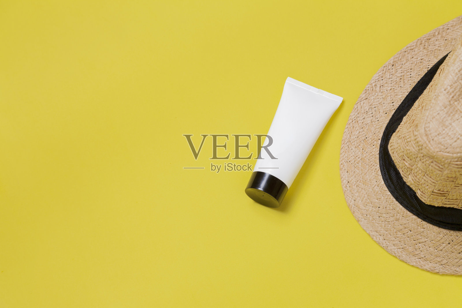 草帽上的黄色背景与白色包装的面部保湿霜。文本空间照片摄影图片