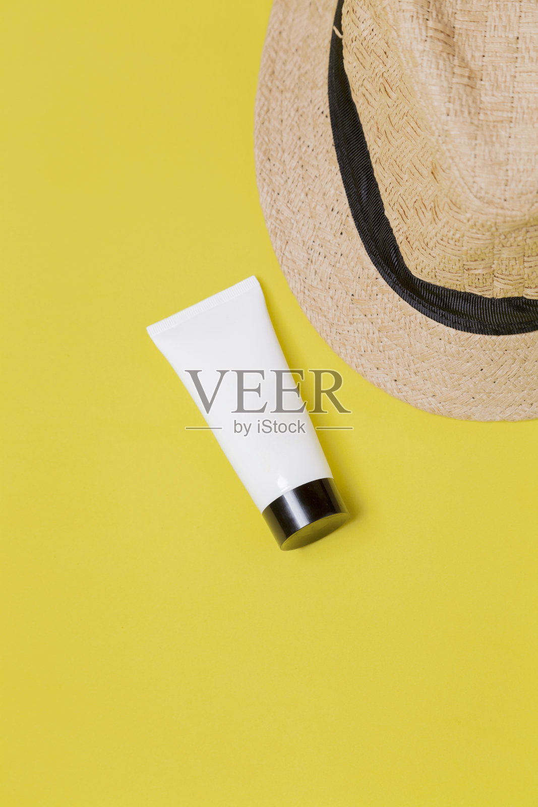 草帽上的黄色背景与白色包装的面部保湿霜。文本空间照片摄影图片