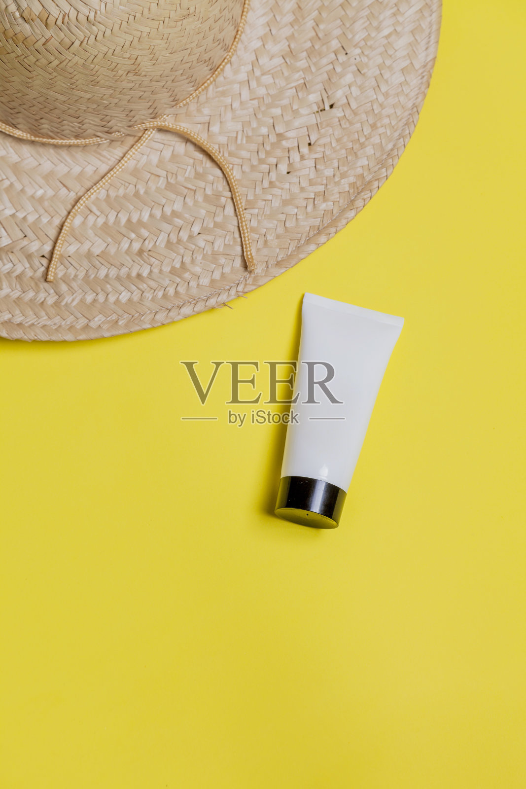 草帽上的黄色背景与白色包装的面部保湿霜。文本空间照片摄影图片