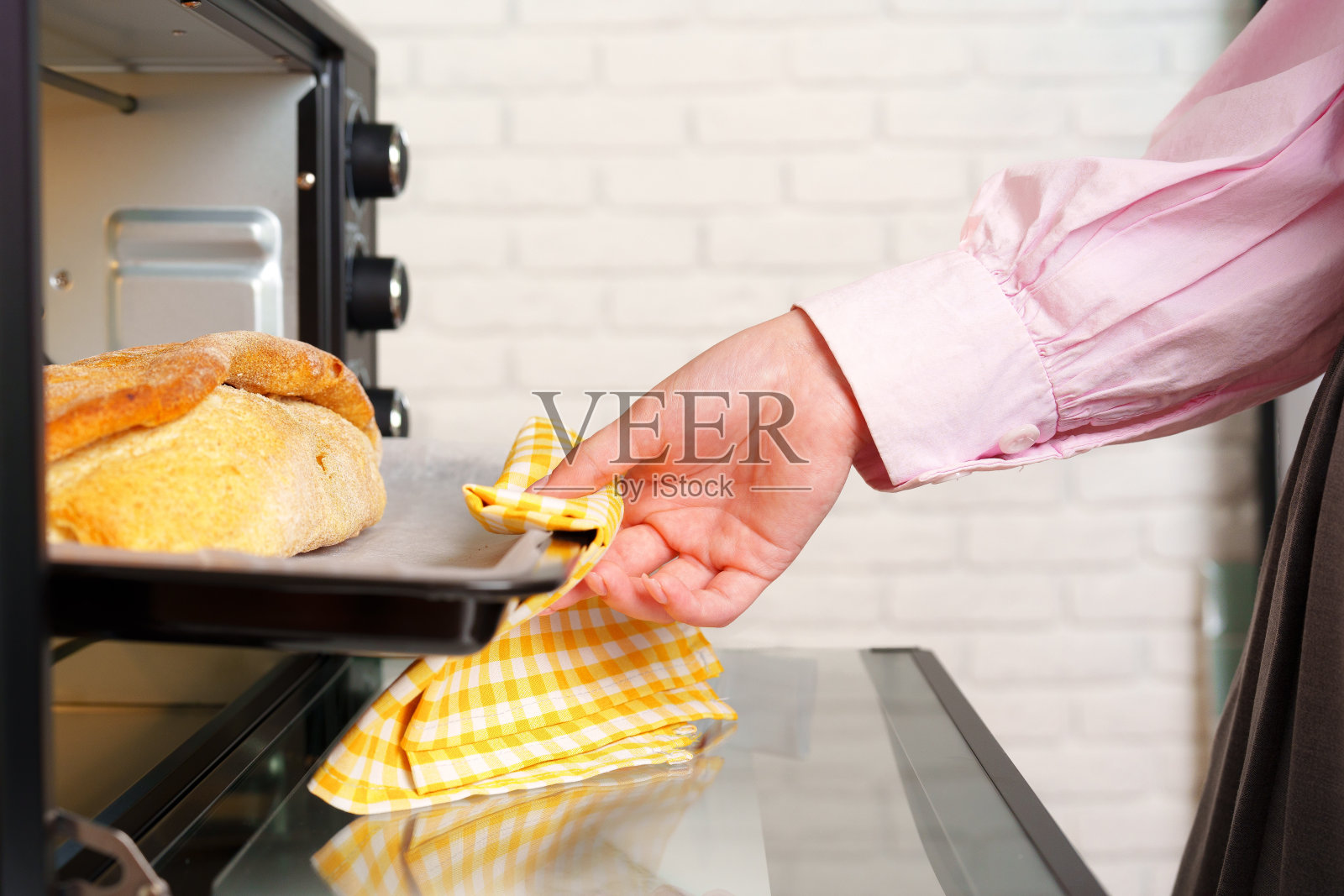 女人的手从迷你烤箱中取出新鲜的面包照片摄影图片
