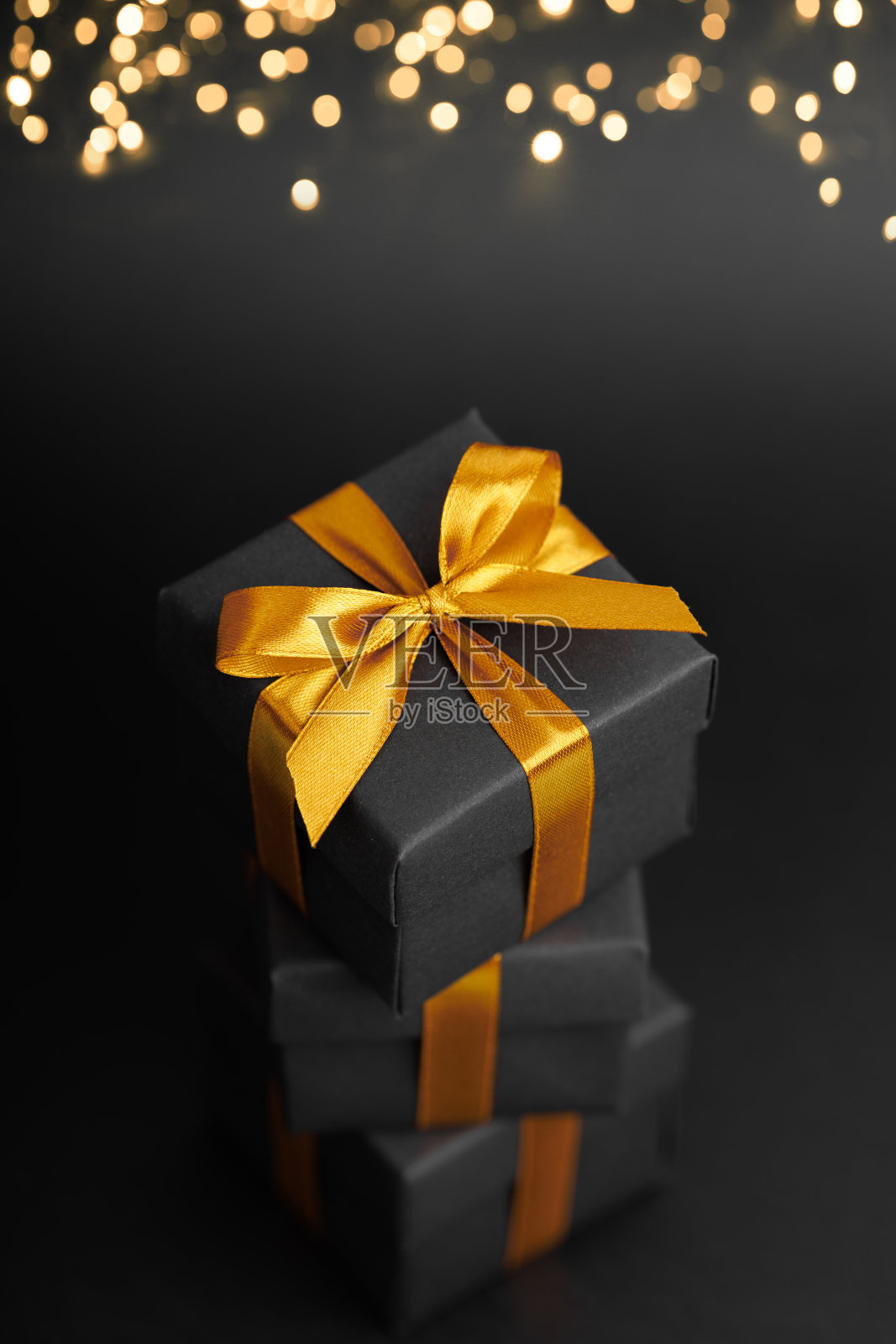 黑色礼品盒与金色丝带蝴蝶结黑色背景照片摄影图片