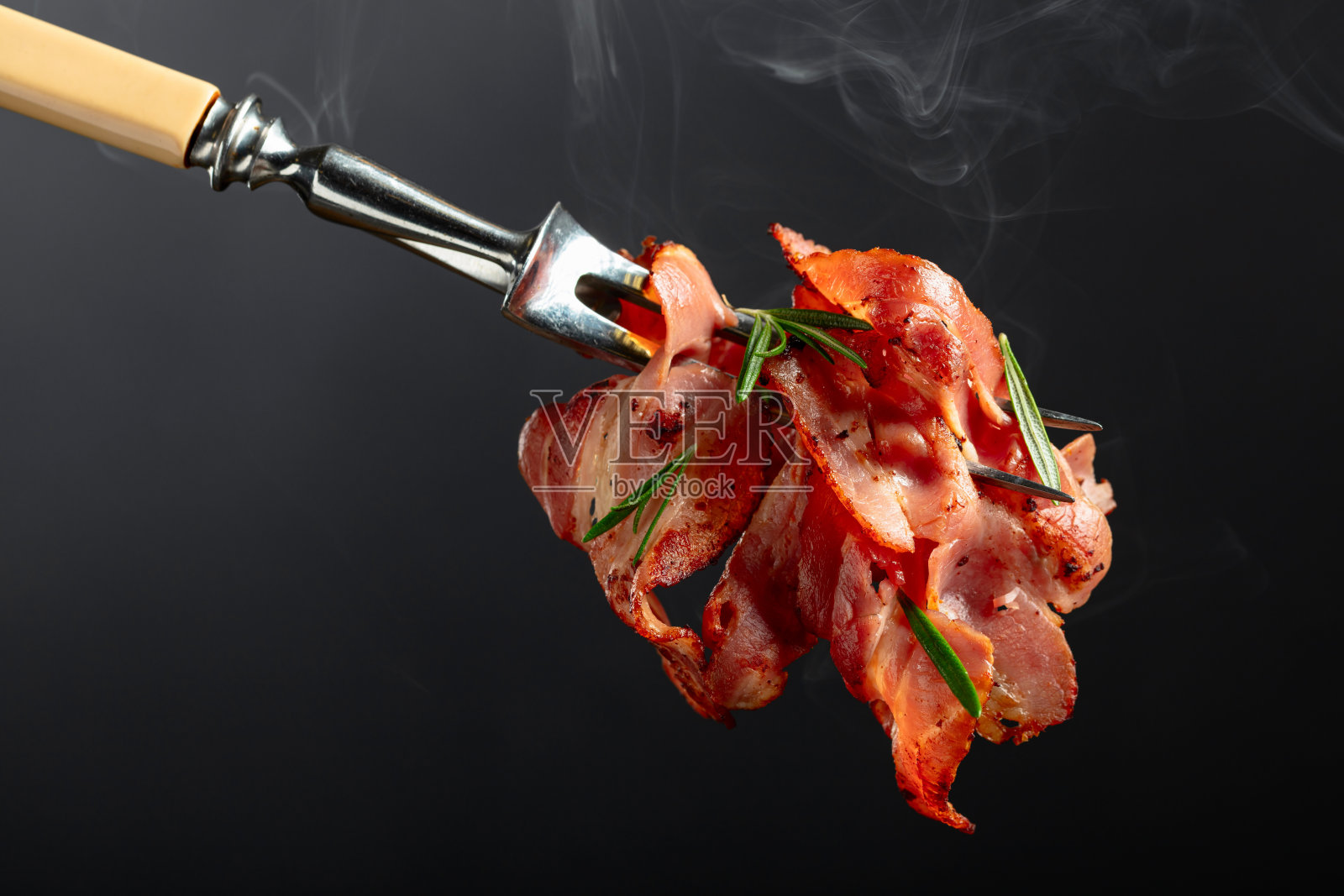 夹着迷迭香的热煎培根片。照片摄影图片