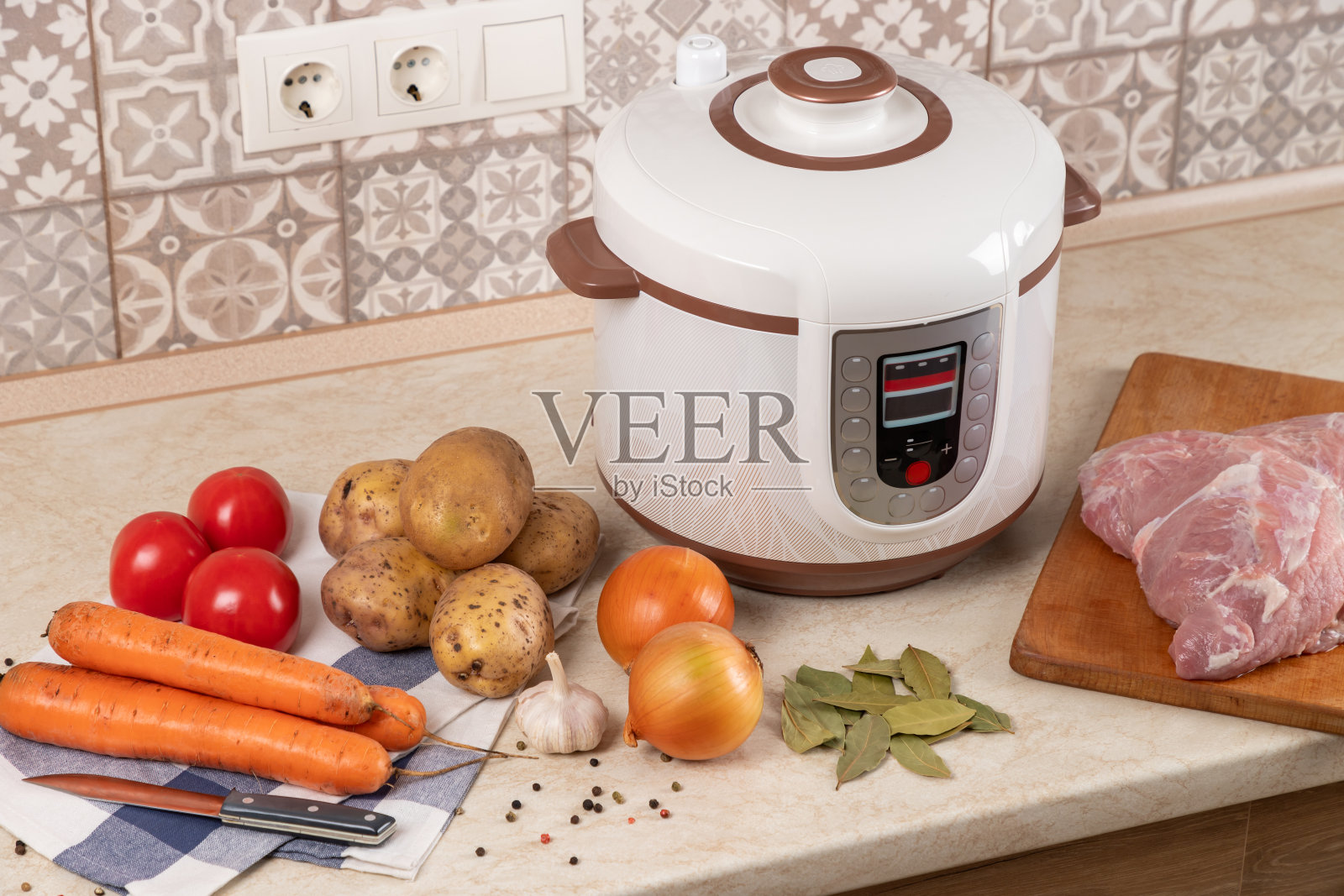 现代，轻型多功能灶具和厨房餐桌上的产品。用炖锅炖土豆和肉。照片摄影图片