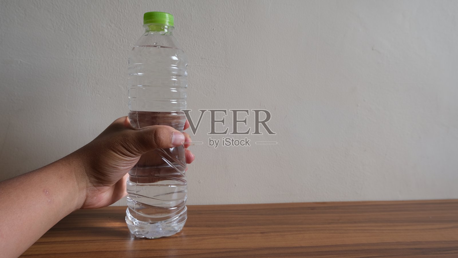 手抓矿泉水的桌子瓶与复制空间照片摄影图片