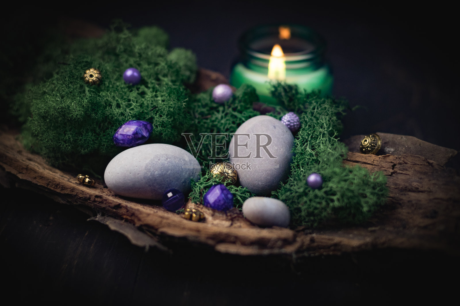 淡紫色，金色的石头躺在树皮上，绿色的苔藓，灰色的石头和黑色的蜡烛上燃烧照片摄影图片