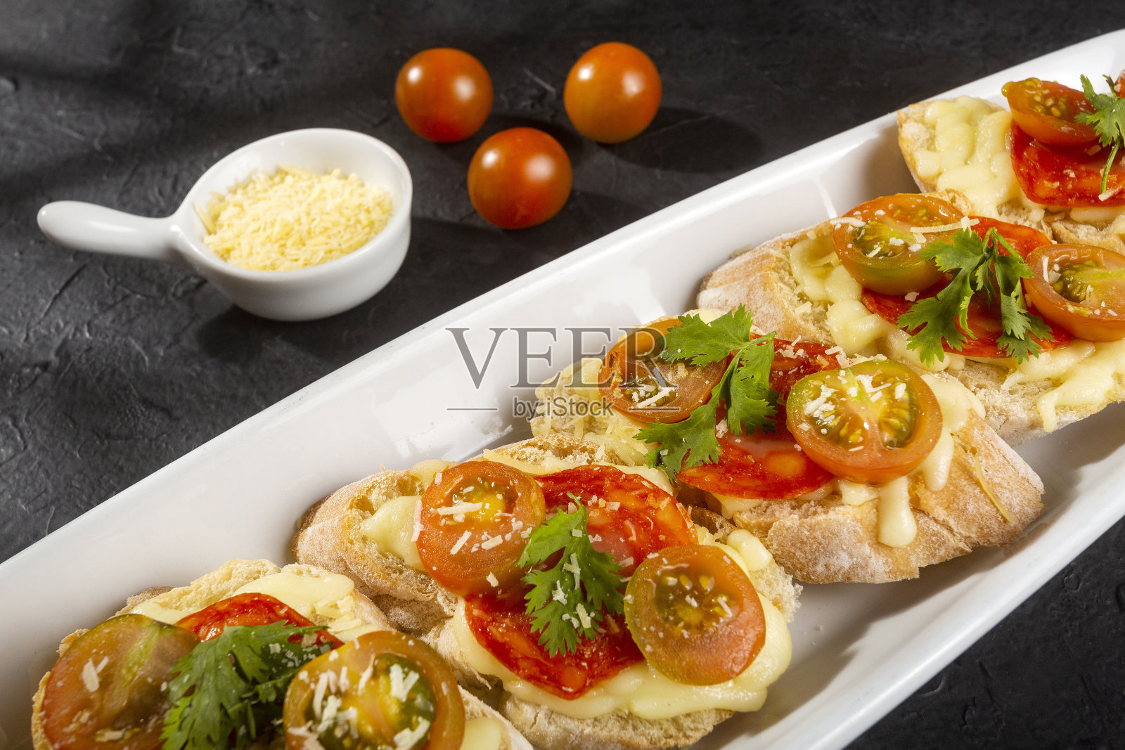 开胃菜或开胃菜——意式烤面包配上西班牙香肠片，配上法式面包，配上圣女果和马苏里拉奶酪照片摄影图片