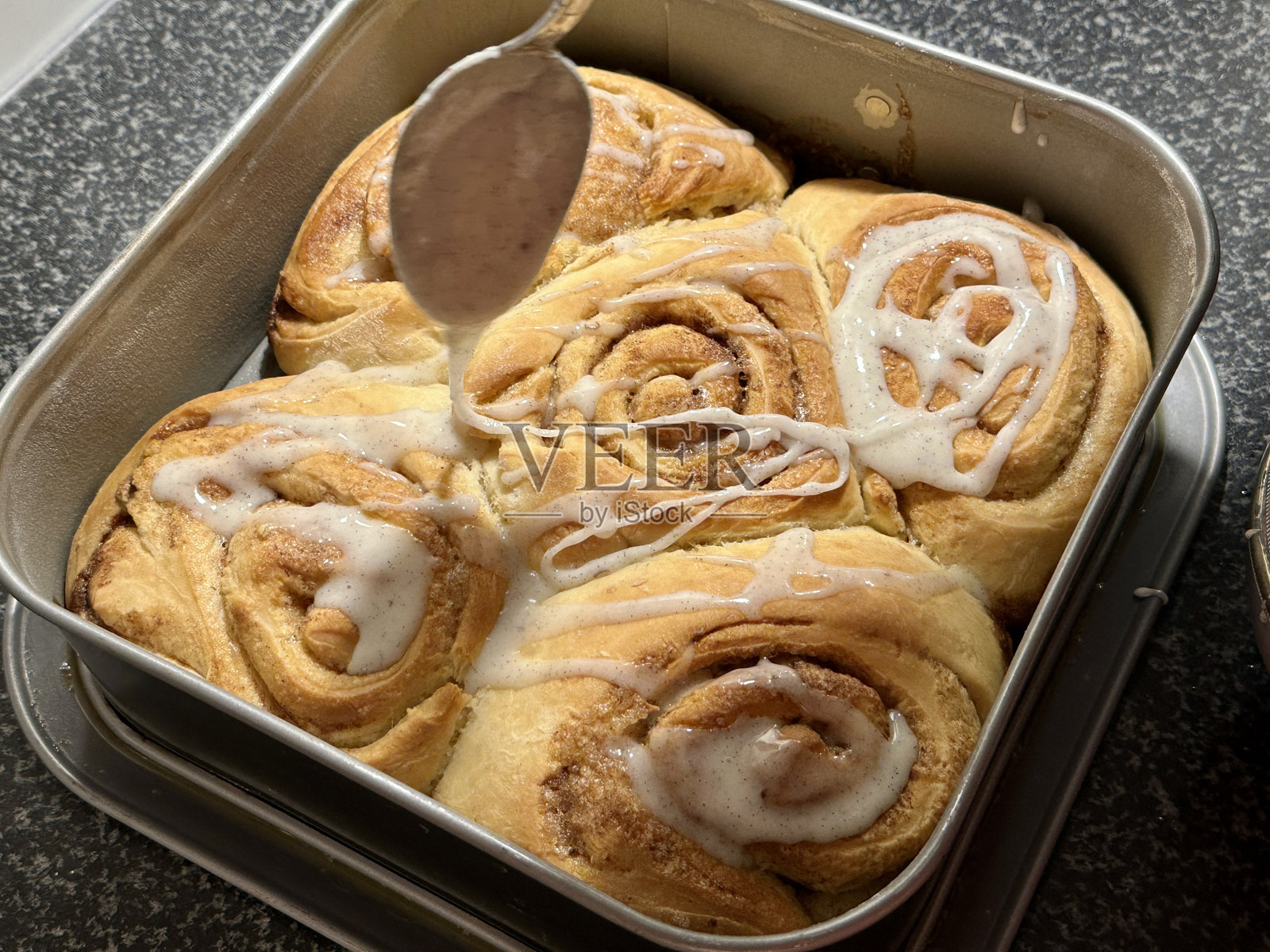 烘烤后给自制的肉桂卷上釉照片摄影图片