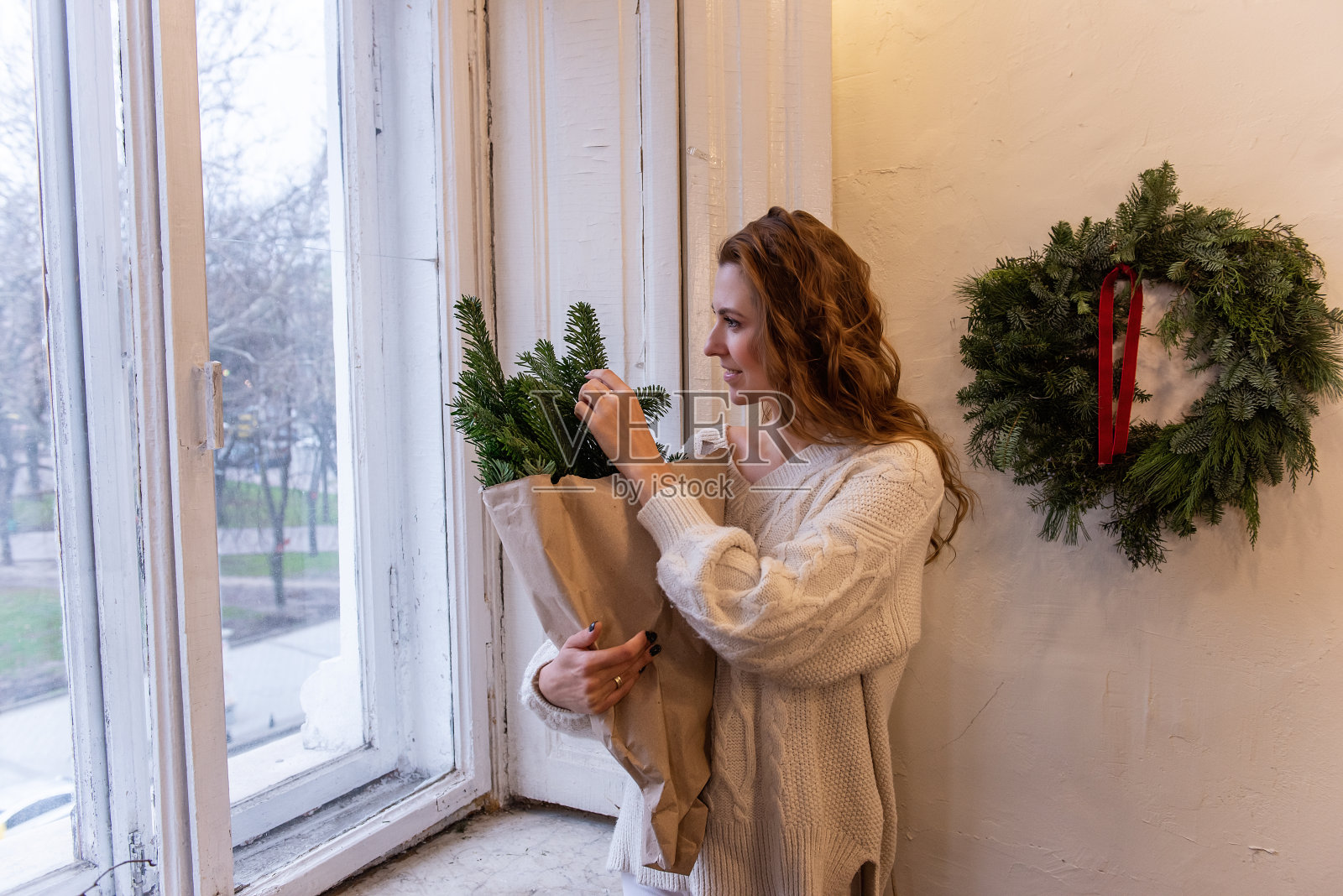 穿着白色针织毛衣的年轻女子的肖像，手里拿着环保的冬季花束照片摄影图片