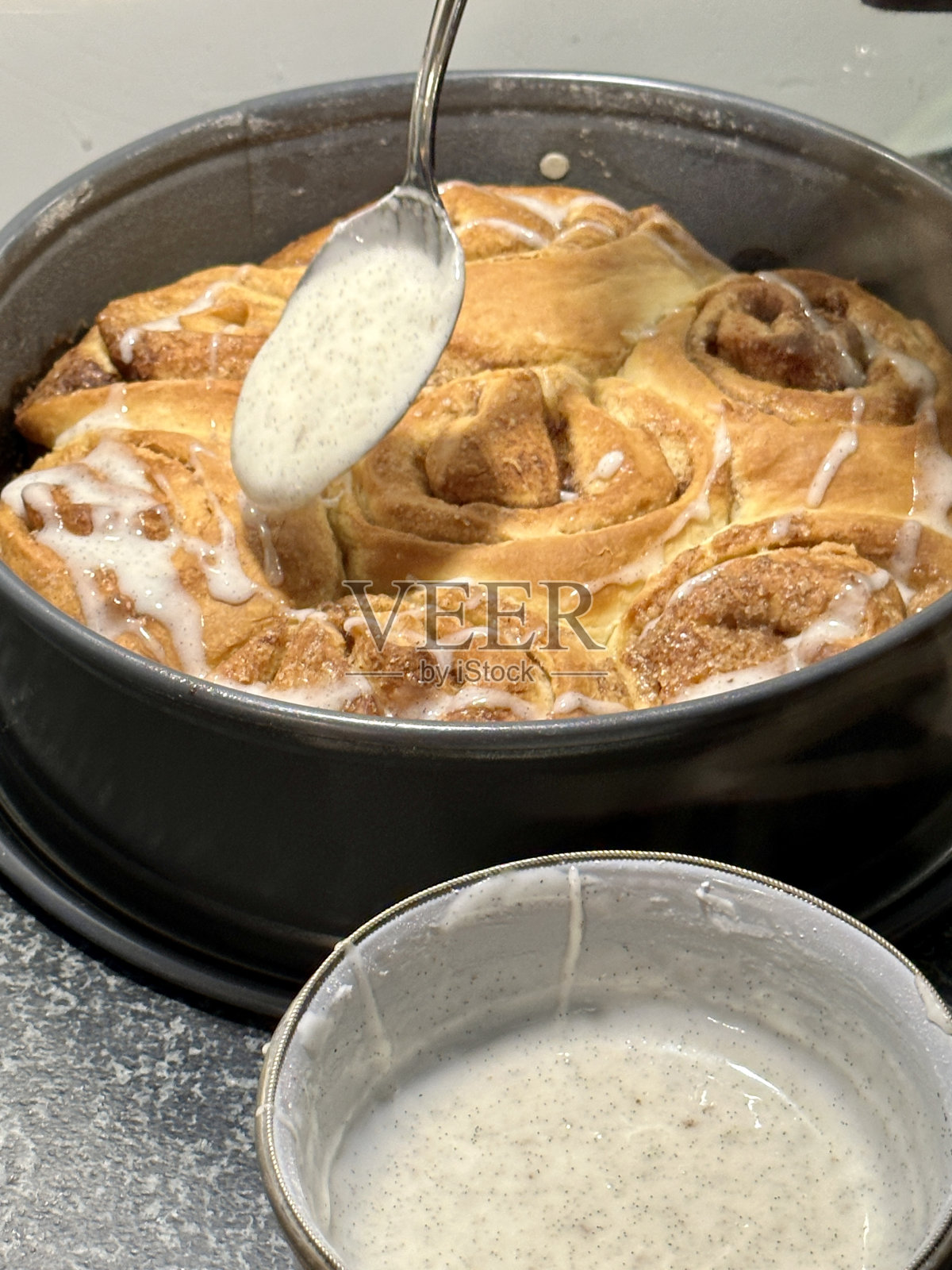 烘烤后给自制的肉桂卷上釉照片摄影图片