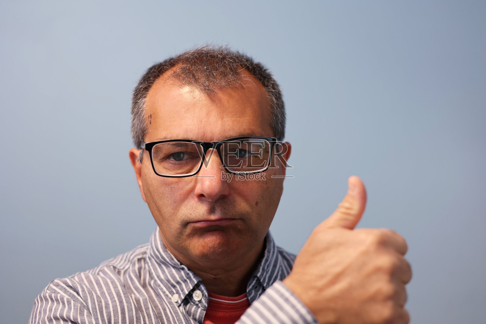一幅戴眼镜的中年男子竖起大拇指的肖像。照片摄影图片