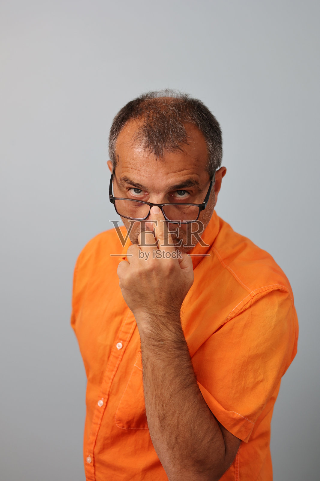 穿着橙色衬衫的成年人正在调整他的眼镜照片摄影图片