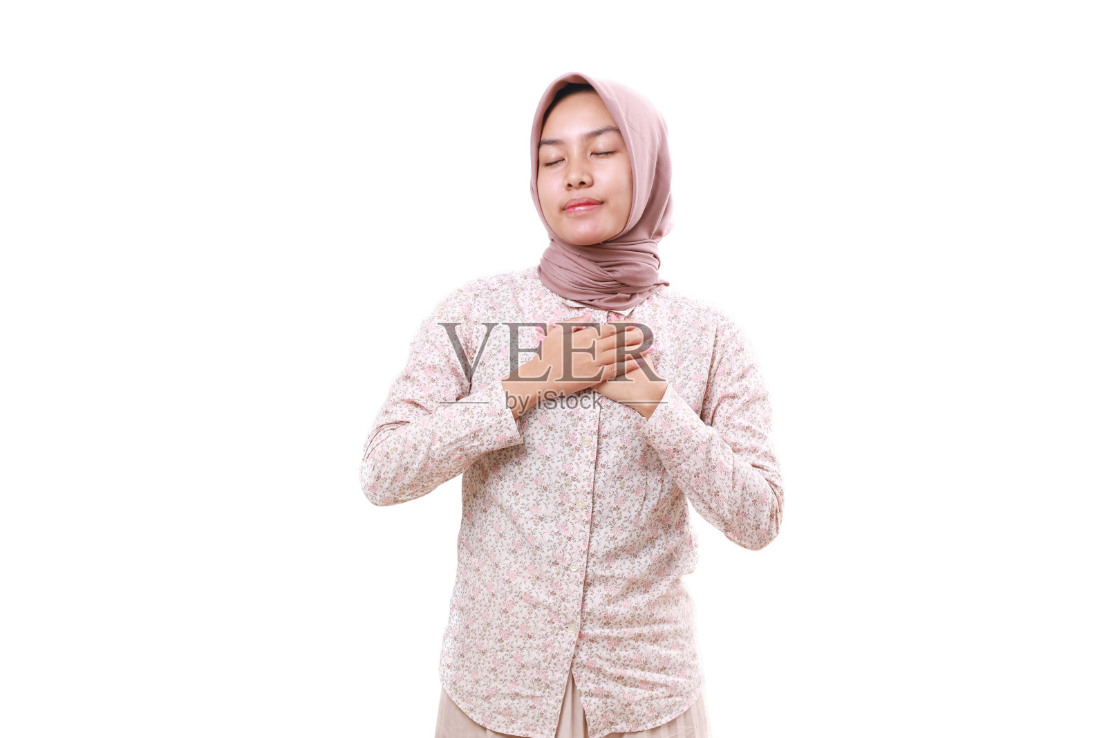 放心年轻的亚洲穆斯林女孩站与闭上眼睛，而触摸她的胸部。孤立于白色照片摄影图片