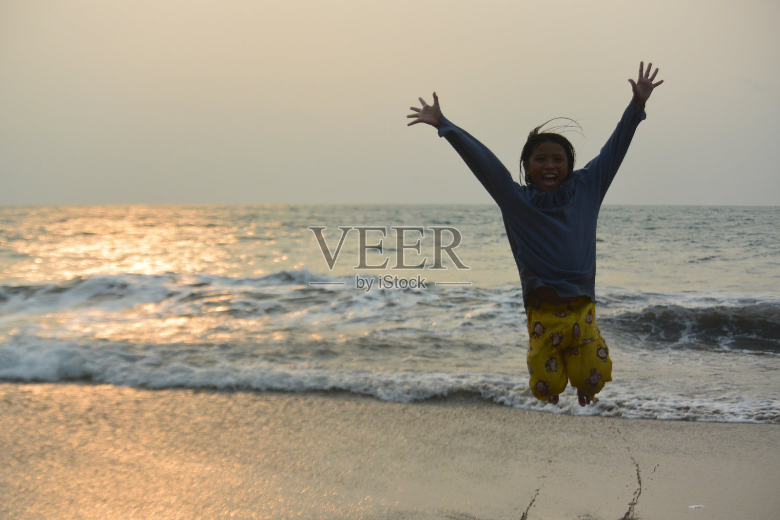 女孩在海滩上跳得很高照片摄影图片