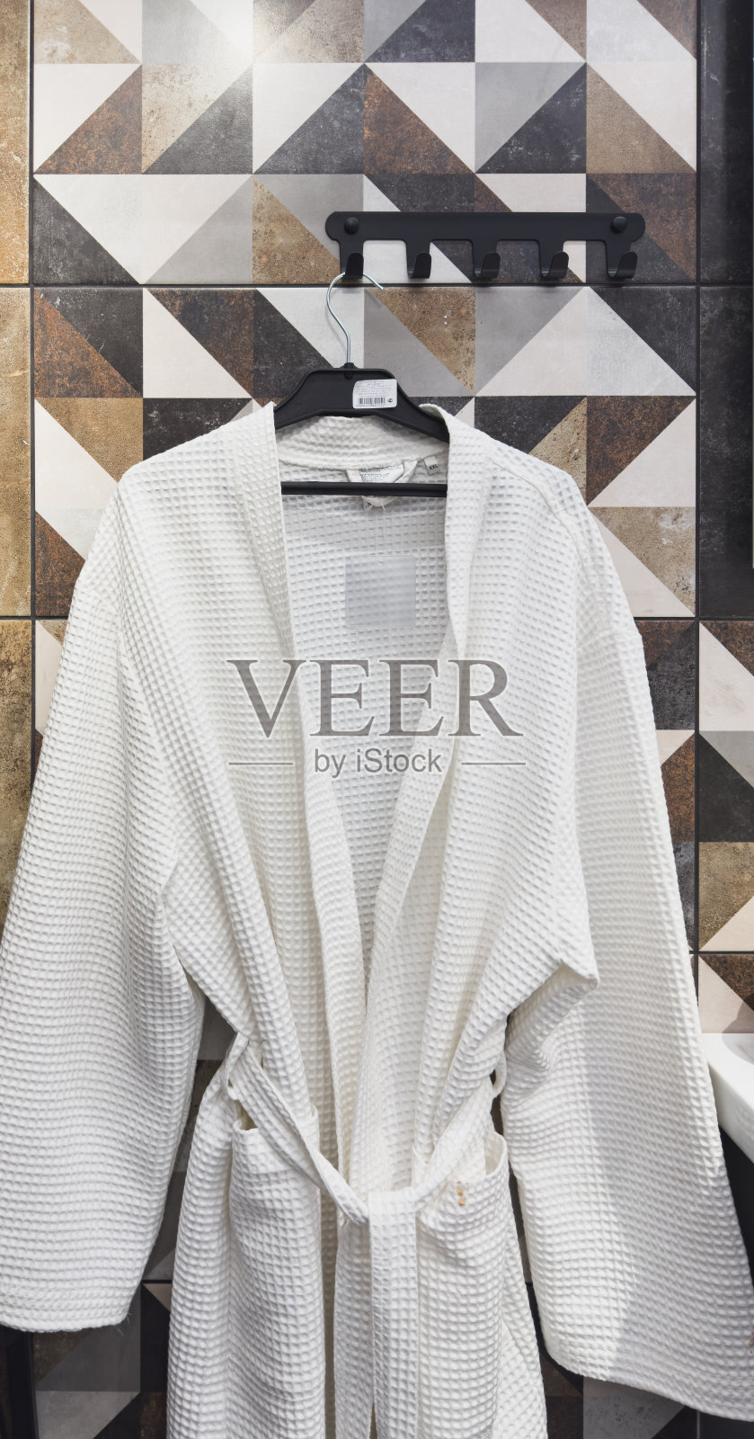 暖白光背景下挂在衣架上的浴袍。照片摄影图片