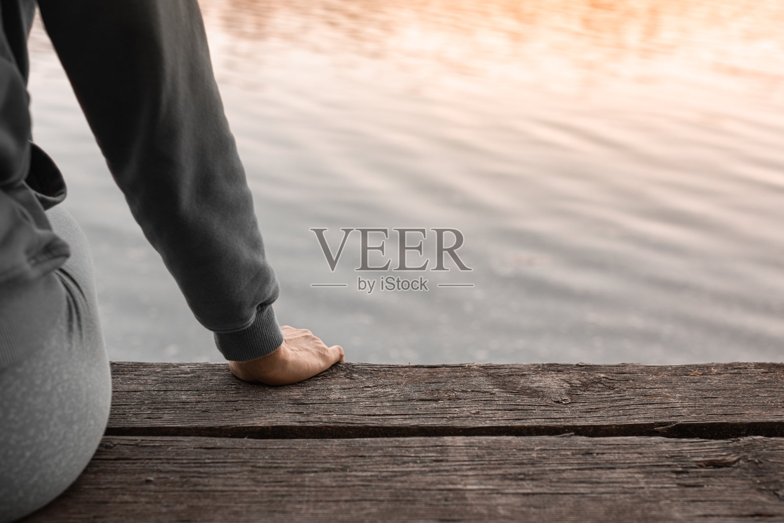 坐在湖边码头边上的女人。照片摄影图片