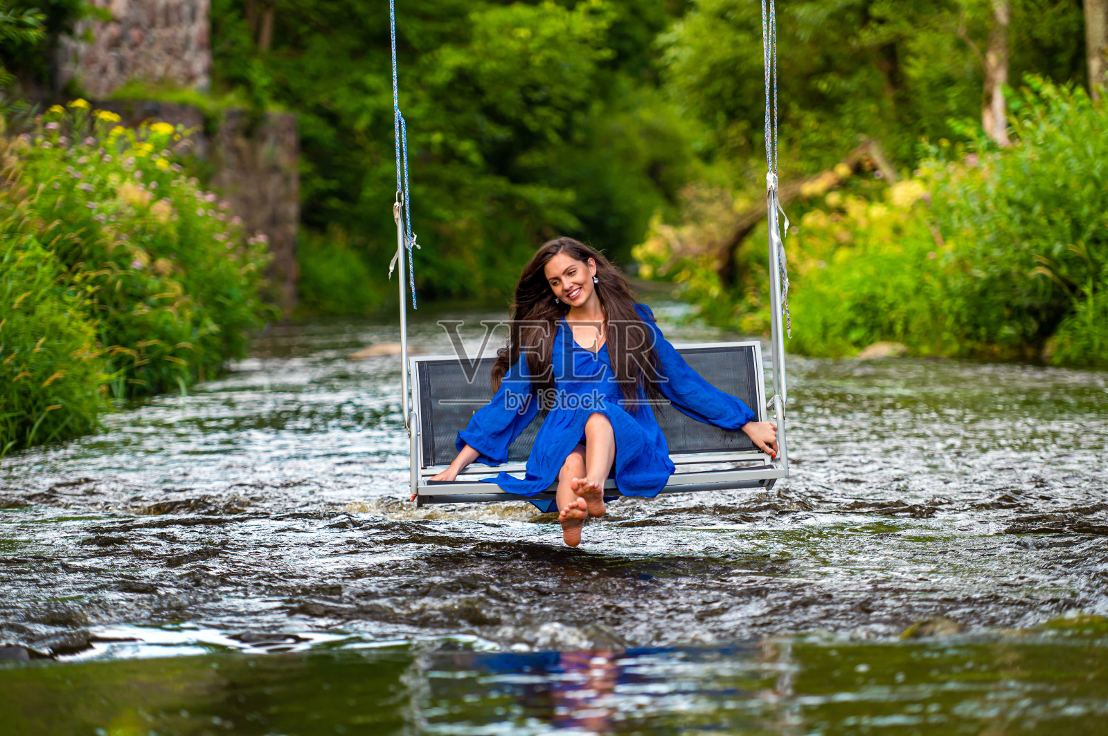 一位快乐的年轻女子在一条湍急的河流上荡秋千照片摄影图片
