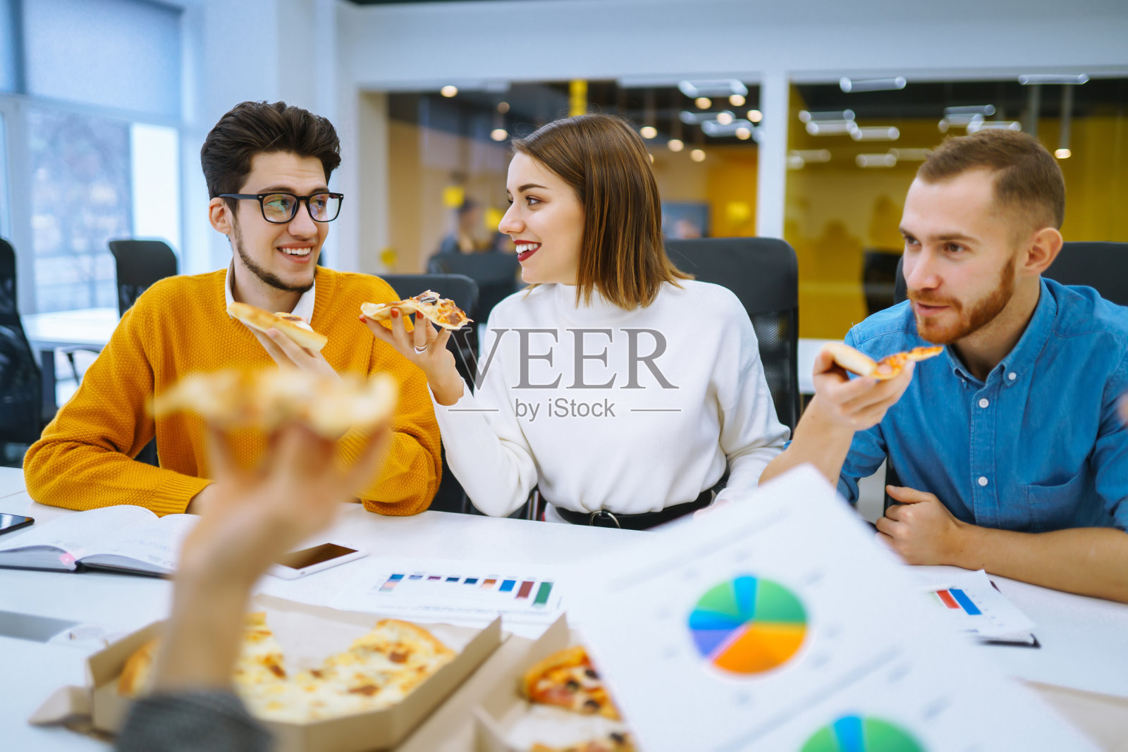 在办公室休息时，兴高采烈的不同员工一起吃披萨。照片摄影图片