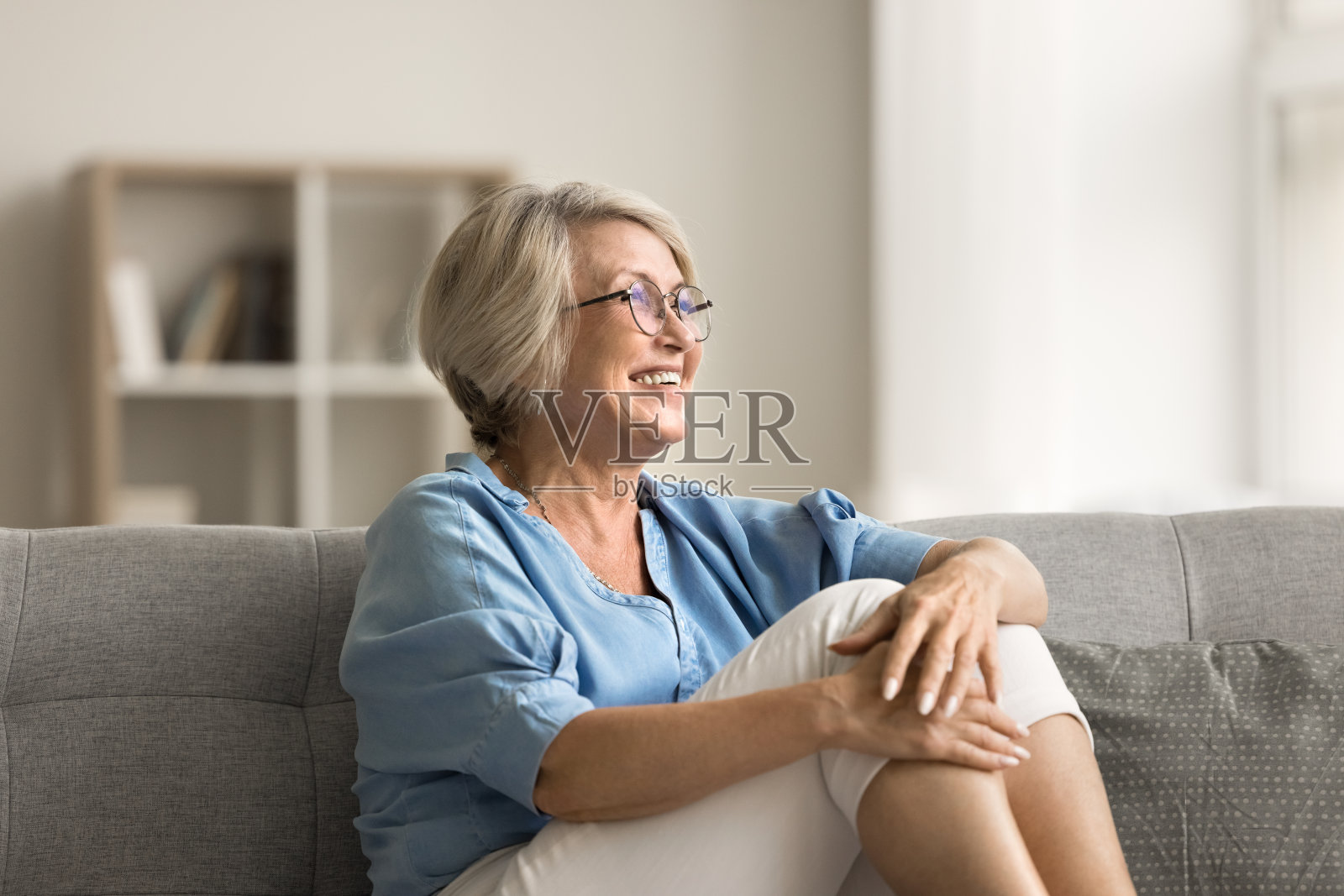 正坐在家里沙发上的金发老女人照片摄影图片