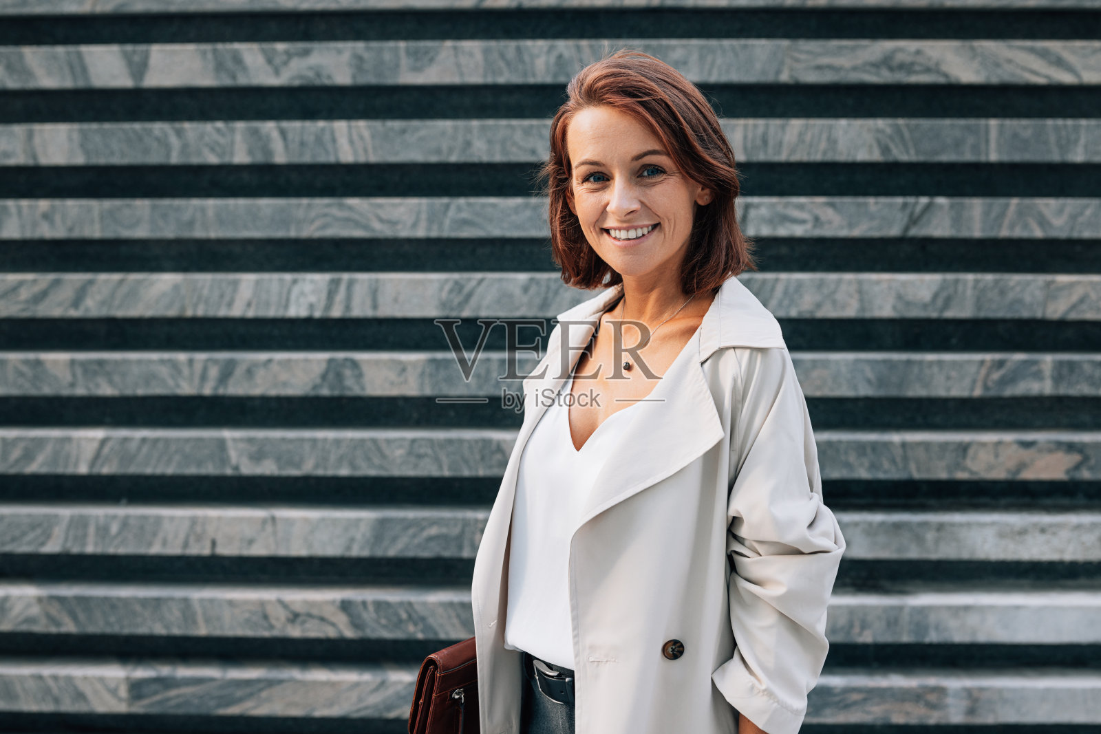 一位姜黄色头发的中年女性站在户外看着镜头，面带微笑照片摄影图片