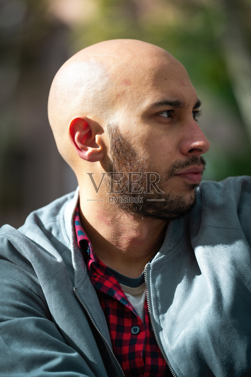 时髦的秃顶，留着胡子的男人穿着红色格子衬衫和夹克，享受着马德里阳光明媚的秋天。照片摄影图片