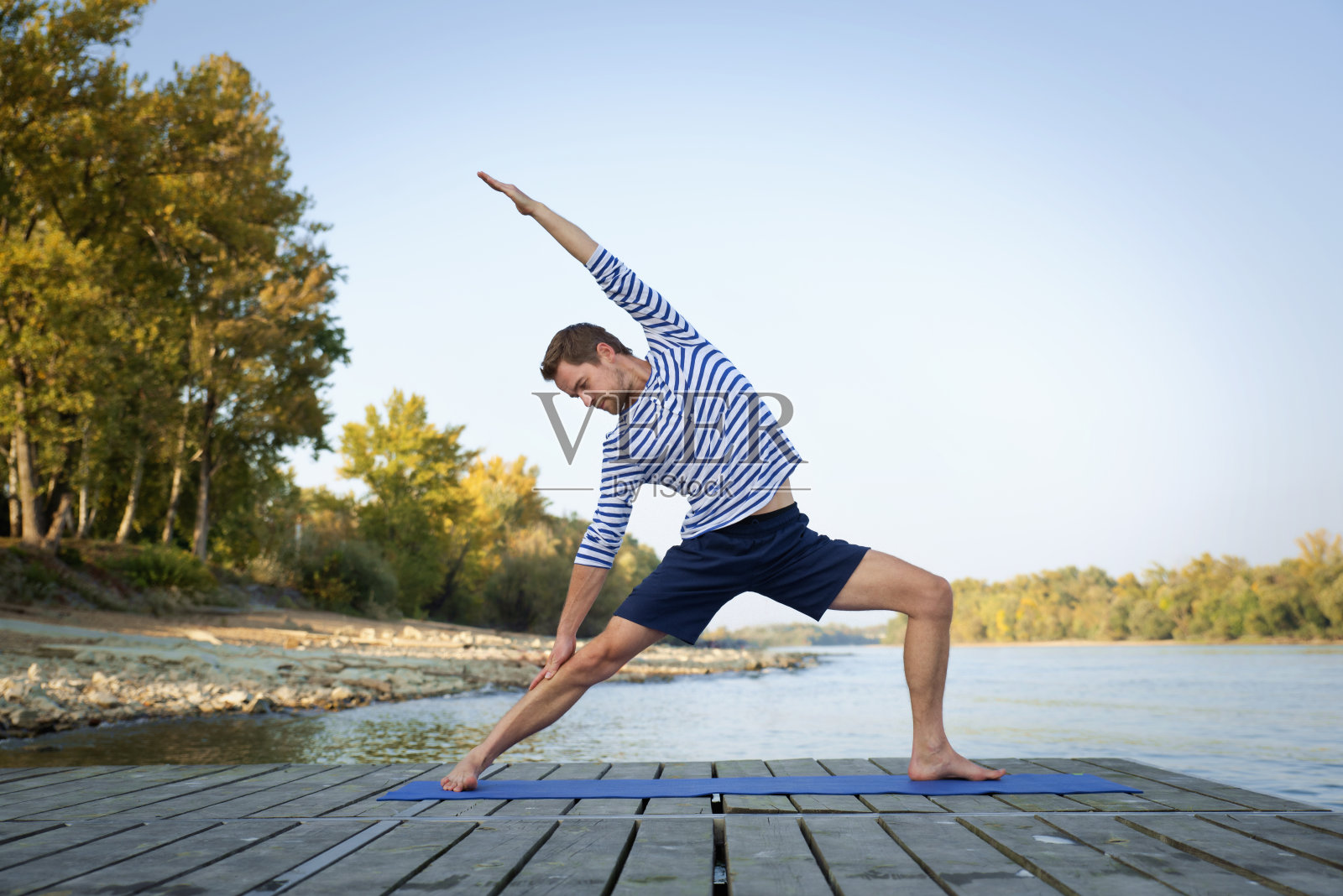 活跃的男子在河边的码头上练习瑜伽照片摄影图片