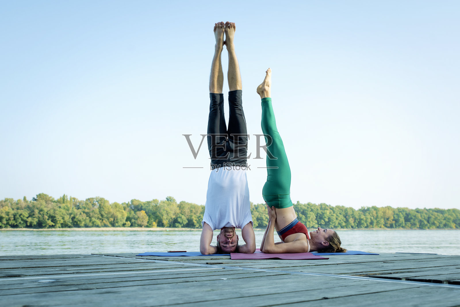 一对情侣在河边的木甲板上练习瑜伽照片摄影图片