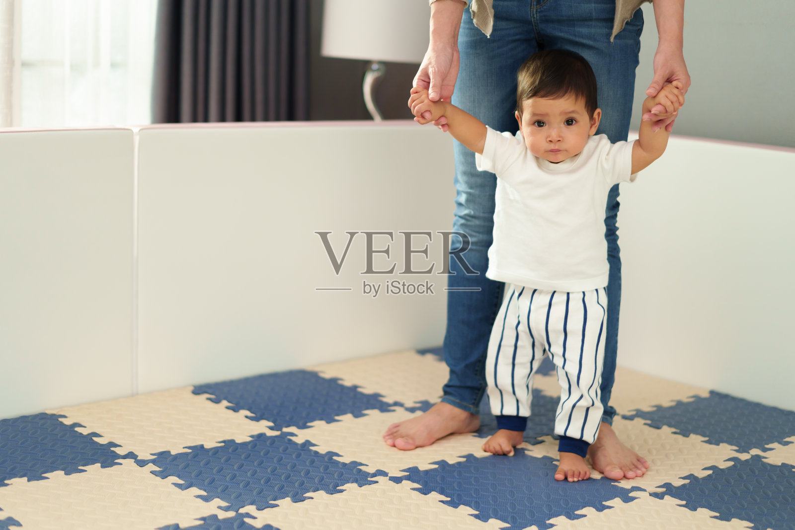 婴儿学着和妈妈一起站在地板上照片摄影图片
