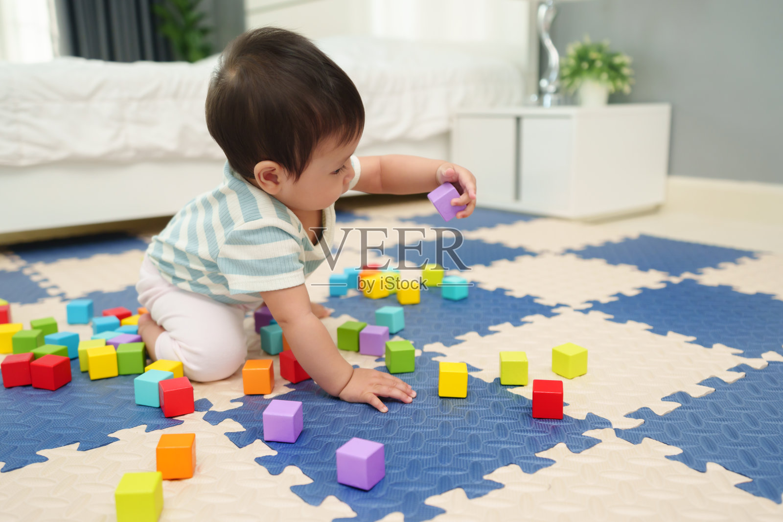 快乐的婴儿在卧室的拼图垫上玩木块玩具照片摄影图片