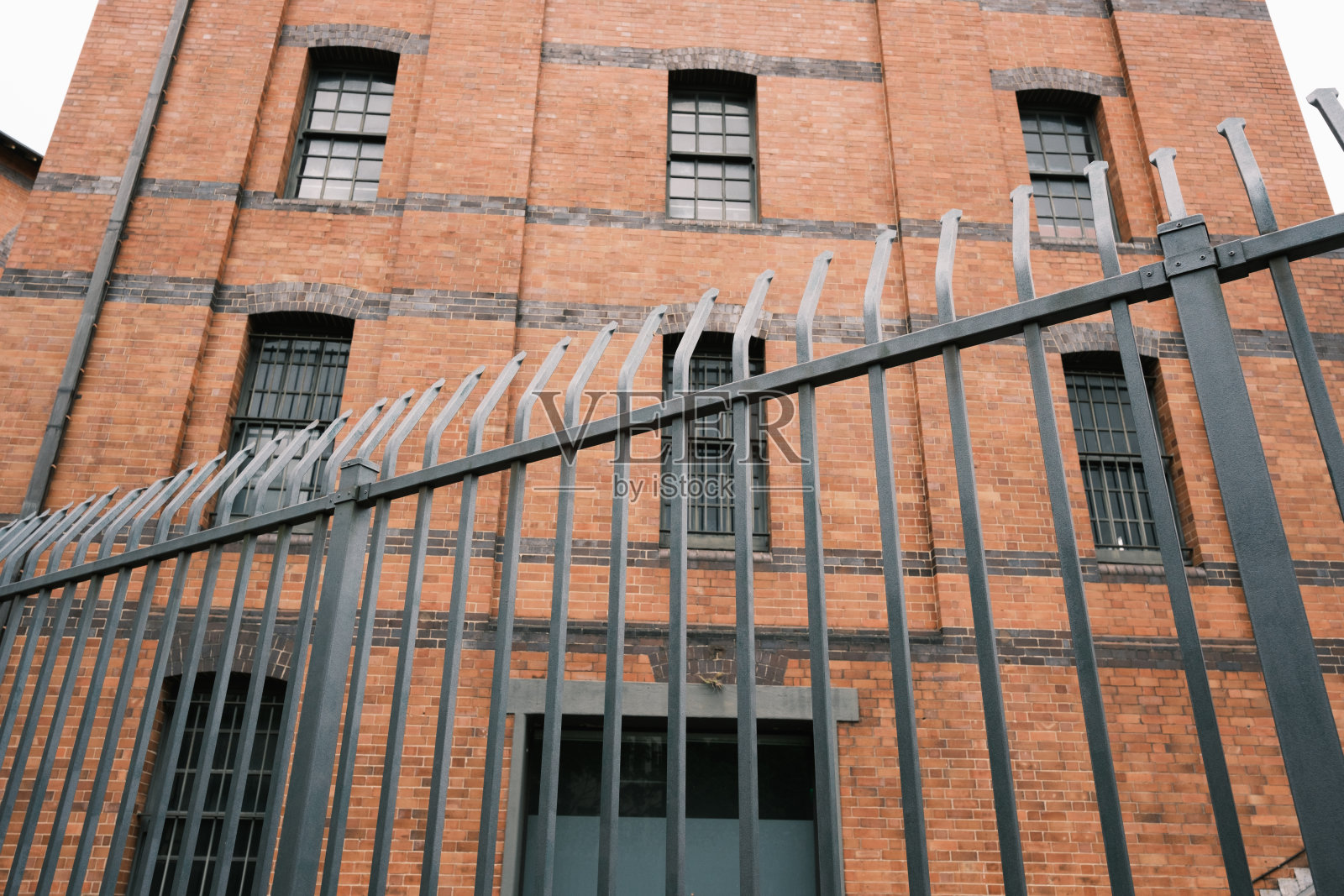 一座老砖房前的尖刺栅栏照片摄影图片