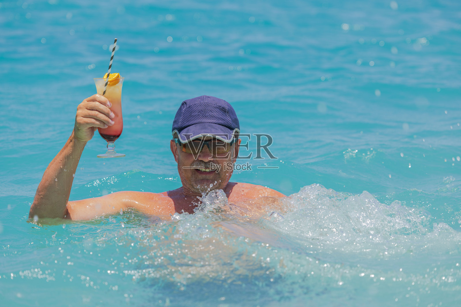 在库拉索岛，一个快乐的人手里拿着鸡尾酒，享受着加勒比海的美景。照片摄影图片